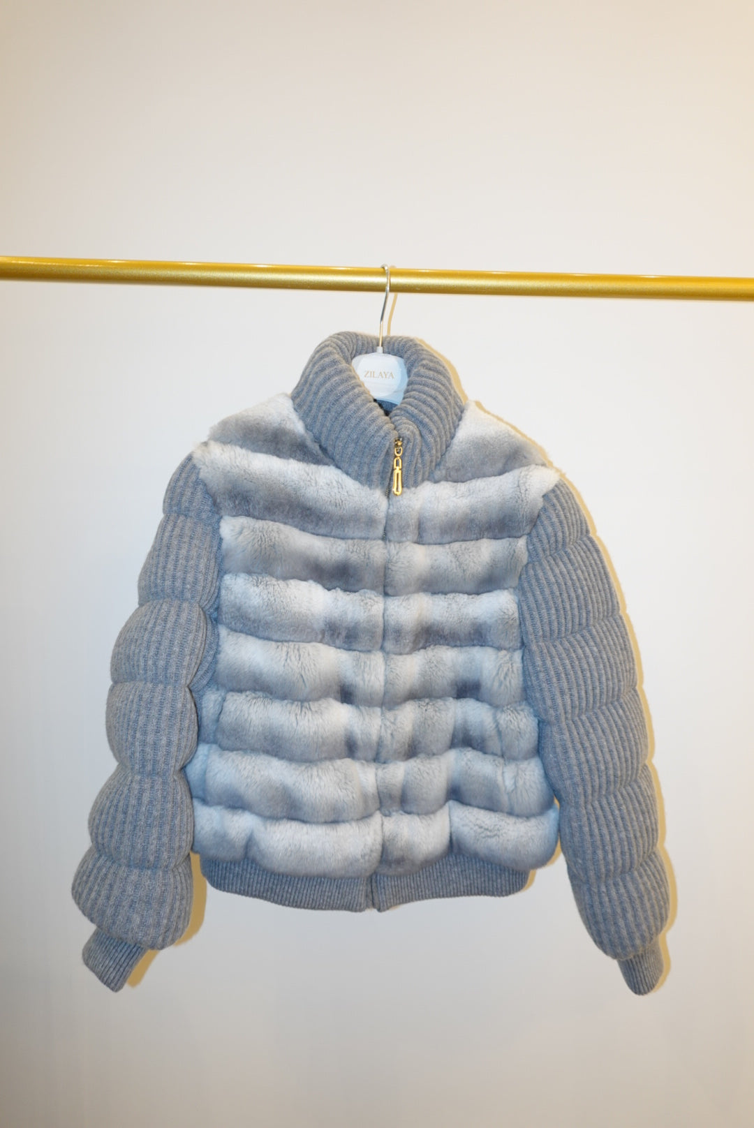 White and gray striped bomber jacket on a hanger against a white background