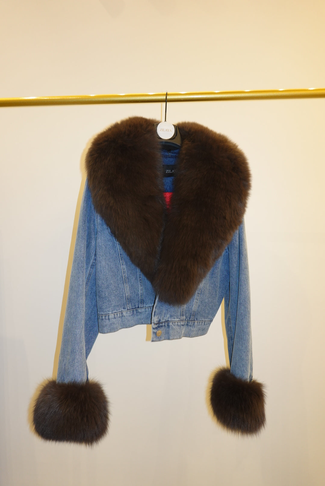 Blue denim jacket with brown fur trim on a white background