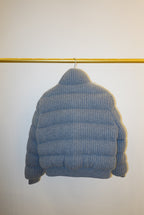 White and gray striped bomber jacket on a hanger against a white background
