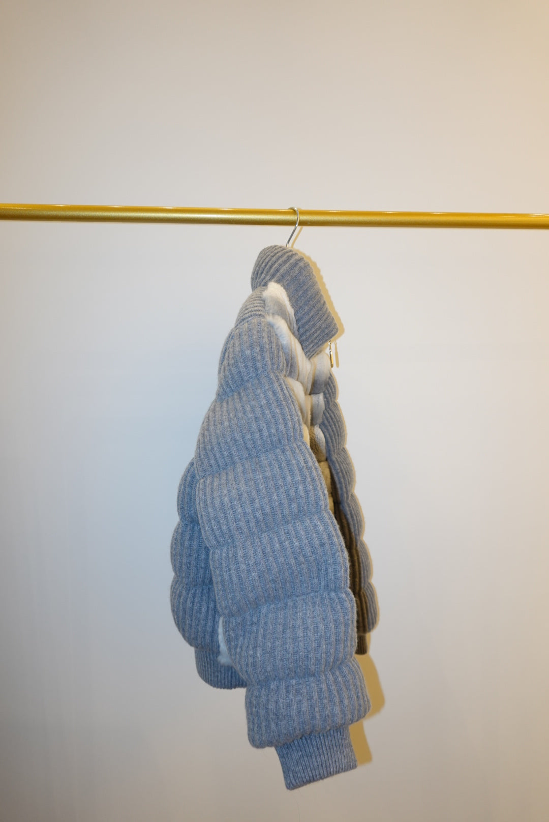 White and gray striped bomber jacket on a hanger against a white background
