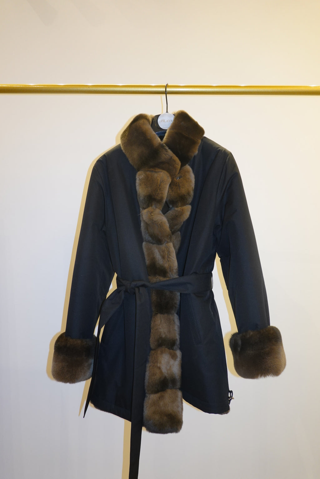 Black coat with brown fur trim against a white background