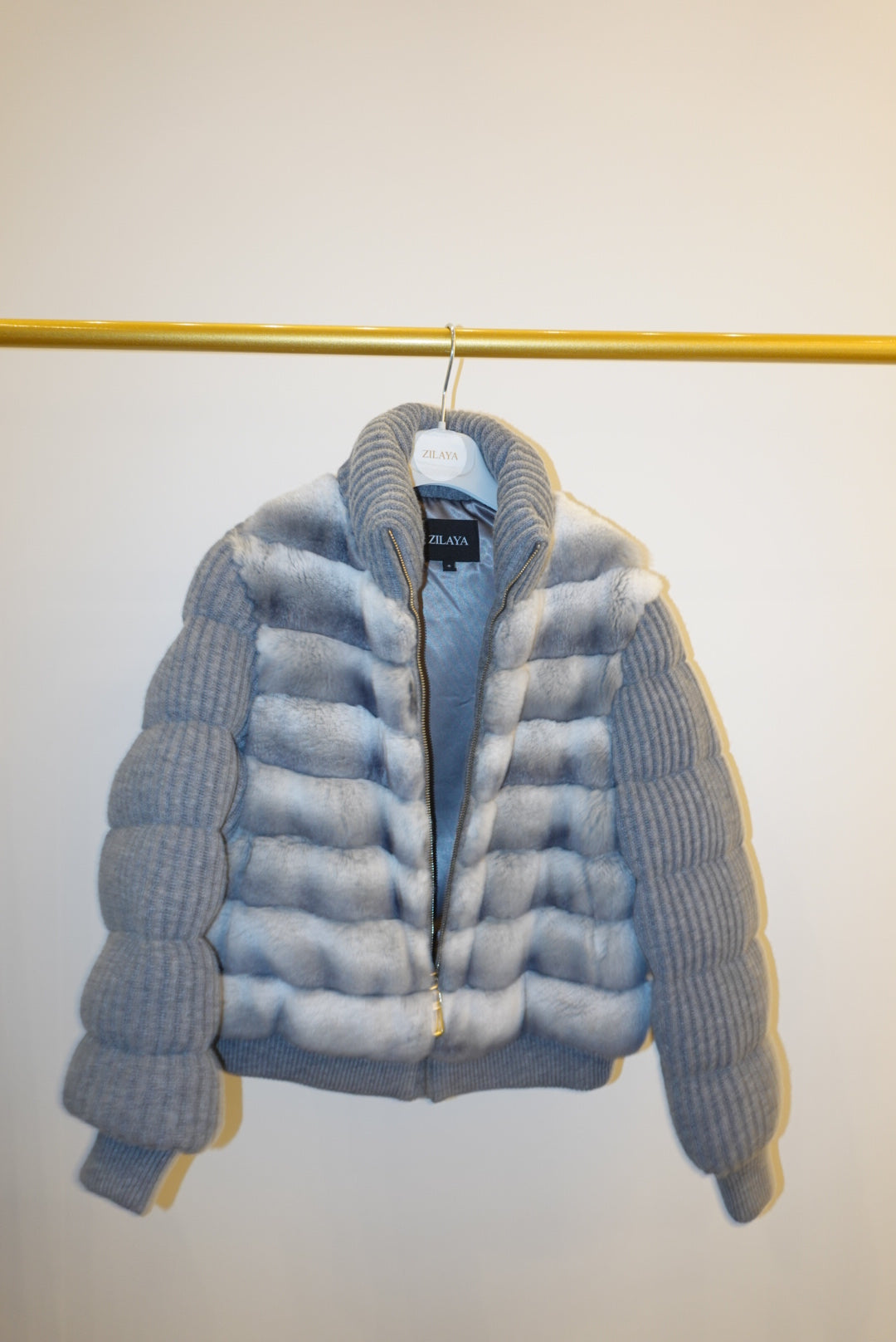 White and gray striped bomber jacket on a hanger against a white background