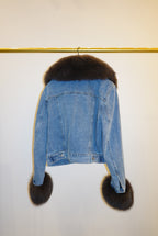 Blue denim jacket with brown fur trim on a white background